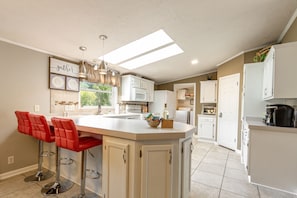 A modern kitchen with a central island, white cabinetry, and red bar stools. - East Asheville - Views - Fire Pit - Parkway - Hiking - Pets - Wi-Fi - Large Home (Asheville)