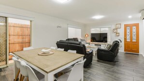 Un salon moderne comprenant un coin repas, un canapé, un téléviseur et un plancher en bois.