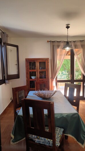 Un espace repas comprenant une table, des chaises, un buffet et une vue par la fenêtre.