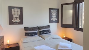 A neatly made bed with two pillows, a bedside table with a lamp, and two wall-mounted artworks. - Viviholidays your holiday villa (Castellammare del Golfo)