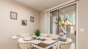 A dining area with a table set for four, surrounded by upholstered chairs, a potted plant, and framed artwork on the wall. - Family-Friendly Luxury Getaway ~ Sleeps 12, Near Golf, Lakes & Festivals (Mesa)