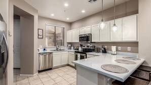 A modern kitchen with white cabinets, stainless steel appliances, and a central island with a light-colored countertop. - Family-Friendly Luxury Getaway ~ Sleeps 12, Near Golf, Lakes & Festivals (Mesa)