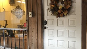 A white door with a wreath, a metal gate, and a doormat with a key symbol.