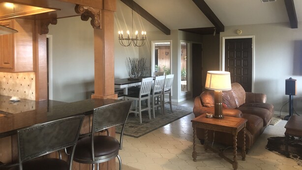 A spacious living room with a high ceiling, a dining area with a chandelier, and a leather sofa.