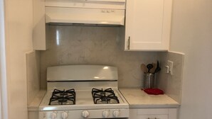 A compact kitchen with a gas stove, oven, and white cabinets. - Entire 3 bedrooms guest property, near Pacific Beach, Downtown，Seaworld，LaJolla (San Diego)