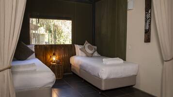 A room with two beds, a window, a wall-mounted zebra head sculpture, and a small lantern on a side table.