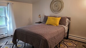 Ein Schlafzimmer mit einem Bett, einem Nachttisch, einer Lampe und einer Wanddekoration.