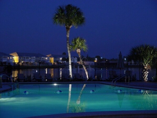 Relax by the pool surrounded by palm trees and lounge chairs.