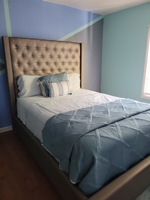 Relax in a cozy bedroom with a large bed featuring a tufted headboard and quilted bedspread.