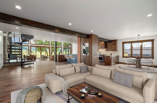 A spacious living area with a large sectional sofa, a dining table, and a kitchen area with wooden cabinets.