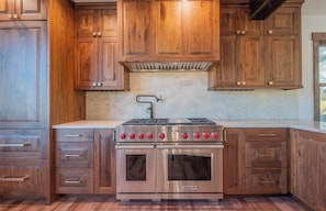 A kitchen with wooden cabinets, a stainless steel stove, and a tiled backsplash.