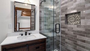 Une salle de bain moderne avec une douche à parois de verre, un lavabo blanc et un meuble-lavabo en bois foncé.