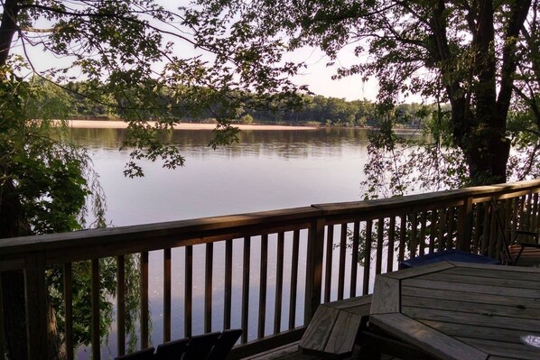 A wooden deck with a view of a calm lake and distant trees.