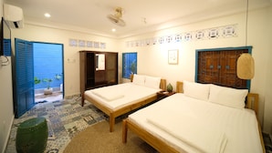 A hotel room with two beds, a small table, a wall-mounted fan, and a potted plant. - K2 Homestay & Coffee - Hostel (Can Tho)