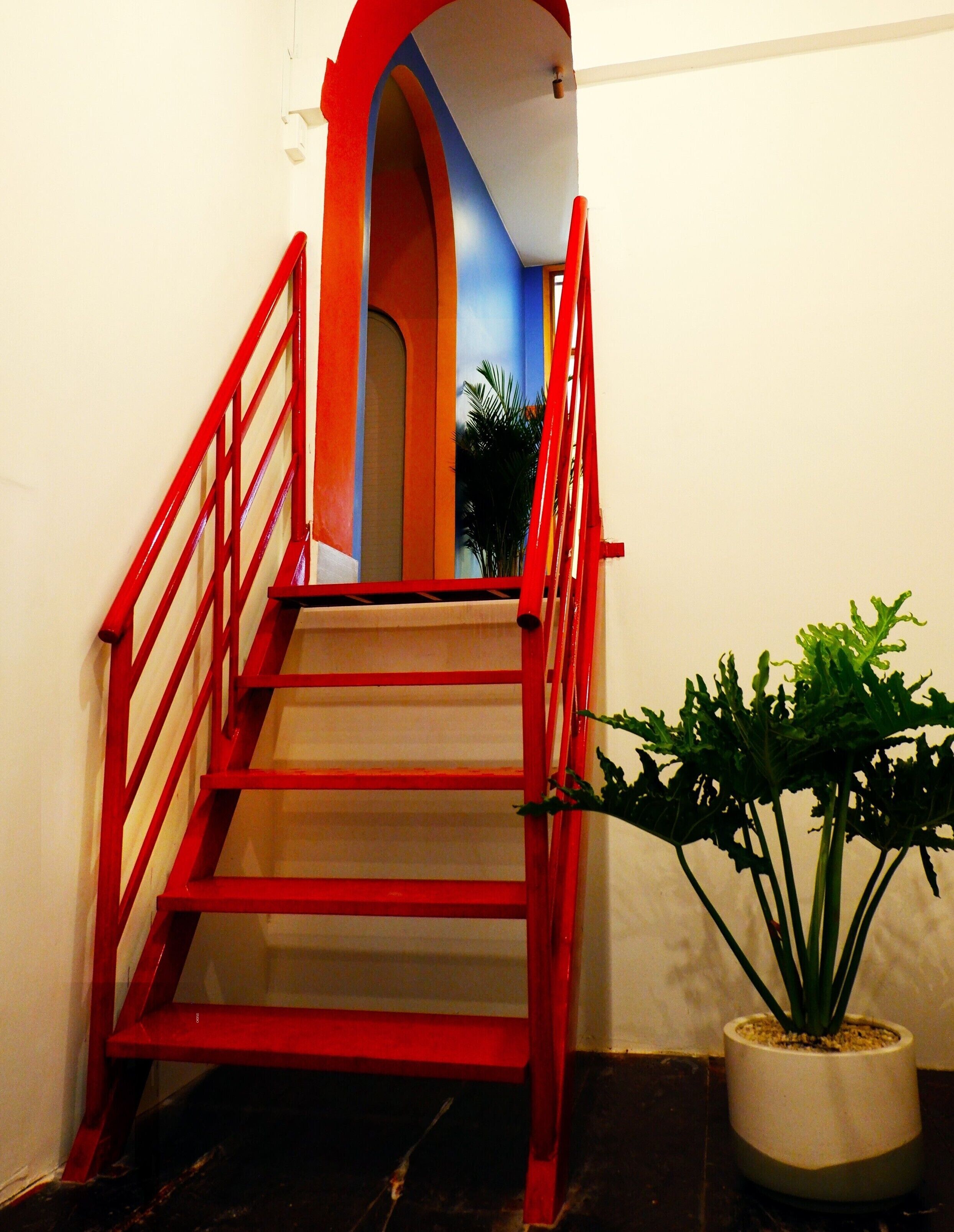 Un escalier avec des rampes rouges menant à un palier.