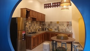 A modern kitchen with wooden cabinets, a black refrigerator, patterned backsplash, and a round table with chairs. - K2 Homestay & Coffee - Hostel (Can Tho)