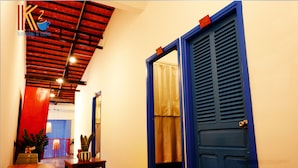 A hallway with a blue door, a wooden table, and a potted plant. - K2 Homestay & Coffee - Hostel (Can Tho)