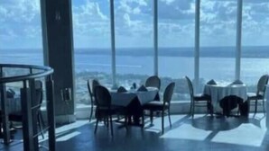 Un espace repas moderne avec une grande table et des chaises, ainsi que de grandes fenêtres offrant une vue sur la mer.