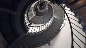 Un escalier en colimaçon avec des rampes en métal et un pilier central.