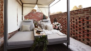 A cozy outdoor seating area with a canopy, cushioned benches, and a table with books and flowers. - Pocheon Hotel Roseto (Pocheon)