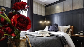 A bedroom with a bed, a nightstand, a vase with red roses, and a wall with a textured panel. - Pocheon Hotel Roseto (Pocheon)