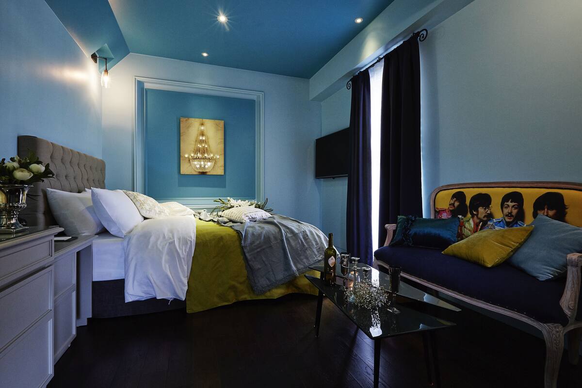 A bedroom with a bed, bedside table, and a sofa.