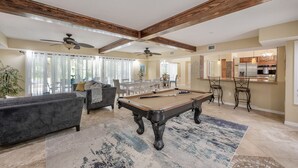 A spacious living room with a pool table, a sofa, and a dining area with chairs. - ✨River Front✨Heated Pool Estate-Large Group,Busch Garden,USF, Sleeps 14 (Tampa)