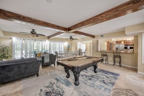 A spacious living room with a pool table, a sofa, and a dining area with chairs. - ✨River Front✨Heated Pool Estate-Large Group,Busch Garden,USF, Sleeps 14 (Tampa)
