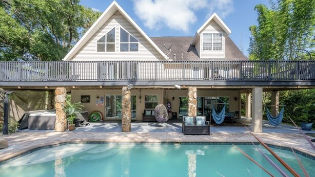 A two-story house with a swimming pool, stone pillars, and a covered patio area. - ✨River Front✨Heated Pool Estate-Large Group,Busch Garden,USF, Sleeps 14 (Tampa)