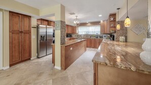A spacious kitchen with wooden cabinets, stainless steel appliances, and a granite countertop. - ✨River Front✨Heated Pool Estate-Large Group,Busch Garden,USF, Sleeps 14 (Tampa)