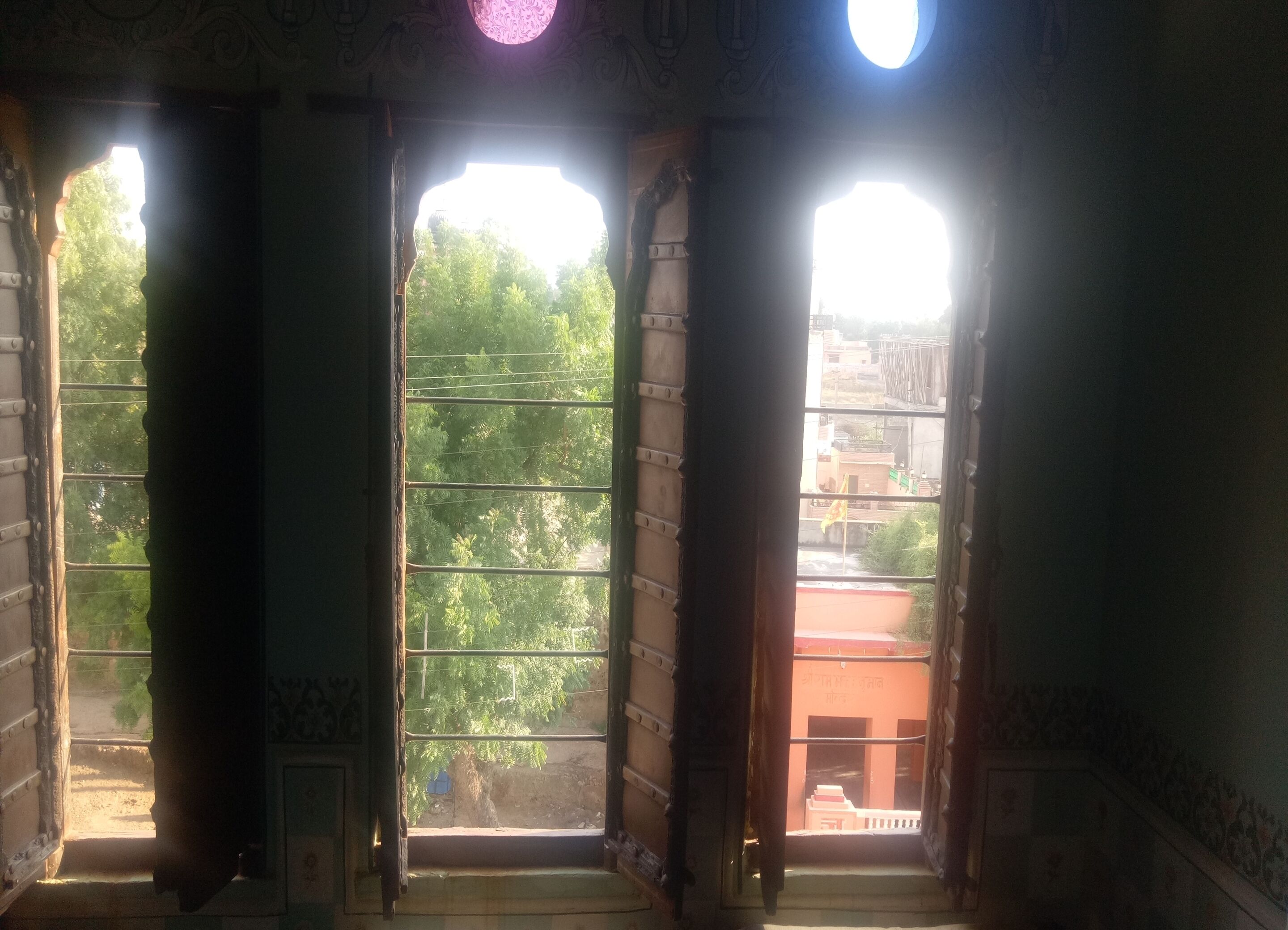 Ein Zimmer mit großen Fenstern, einer Treppe und Blick auf Grün.