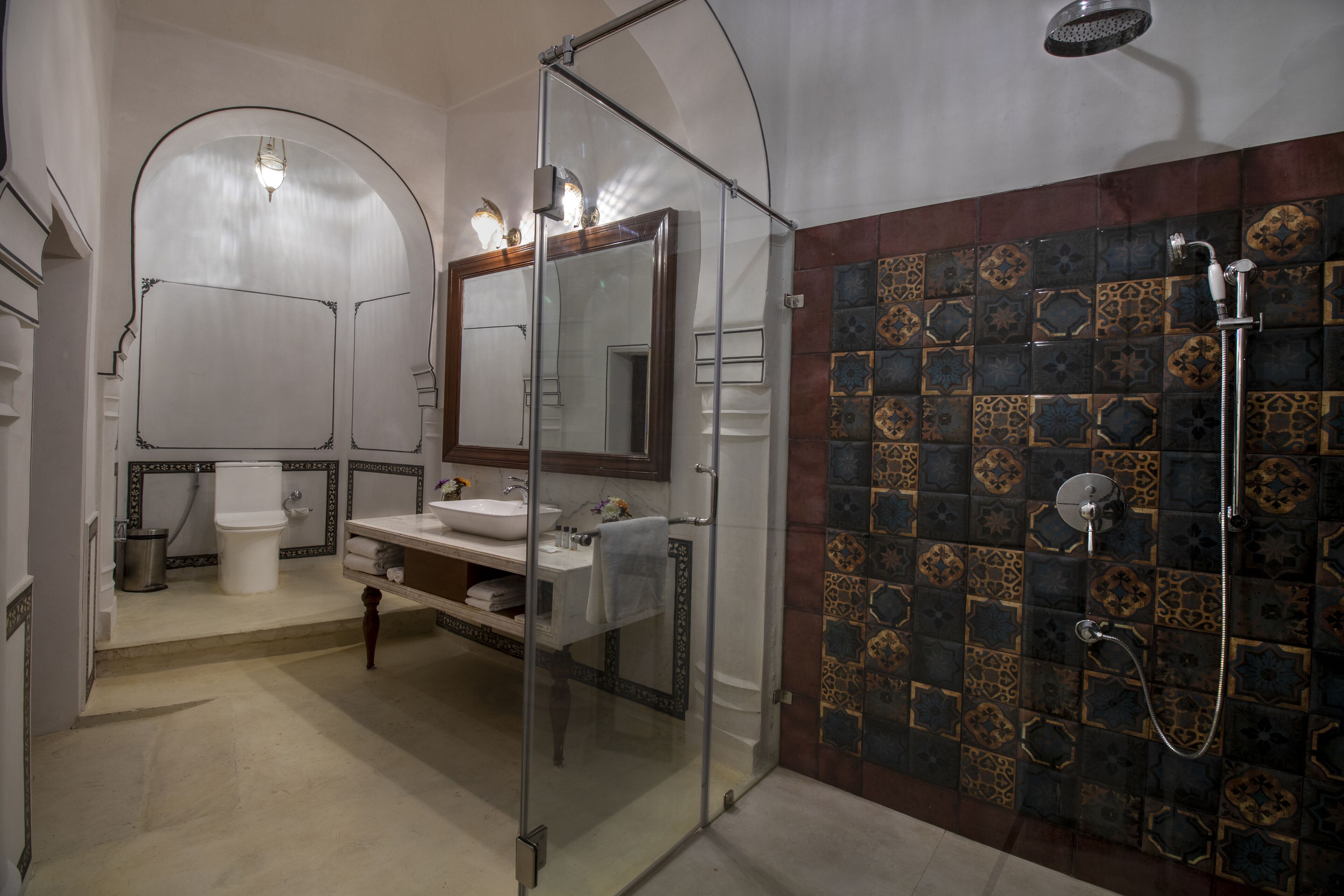 Un bany amb dutxa transparent, un lavabo amb mirall i un vàter.