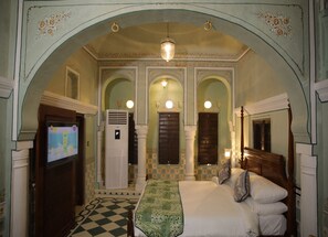 A room with a bed, a television, and an air conditioning unit. - The Legacy Mandawa (Jhunjhunu)