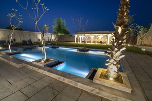 Relax by the serene pool surrounded by lush greenery and comfortable lounge chairs.
