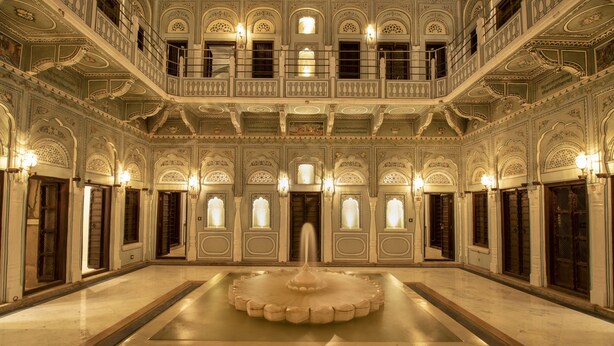 A grand hall with a central fountain, ornate balconies, and multiple windows. - The Legacy Mandawa (Jhunjhunu)