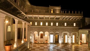 A grand, illuminated courtyard with ornate architecture, featuring a checkered floor and multiple arched doorways. - The Legacy Mandawa (Jhunjhunu)