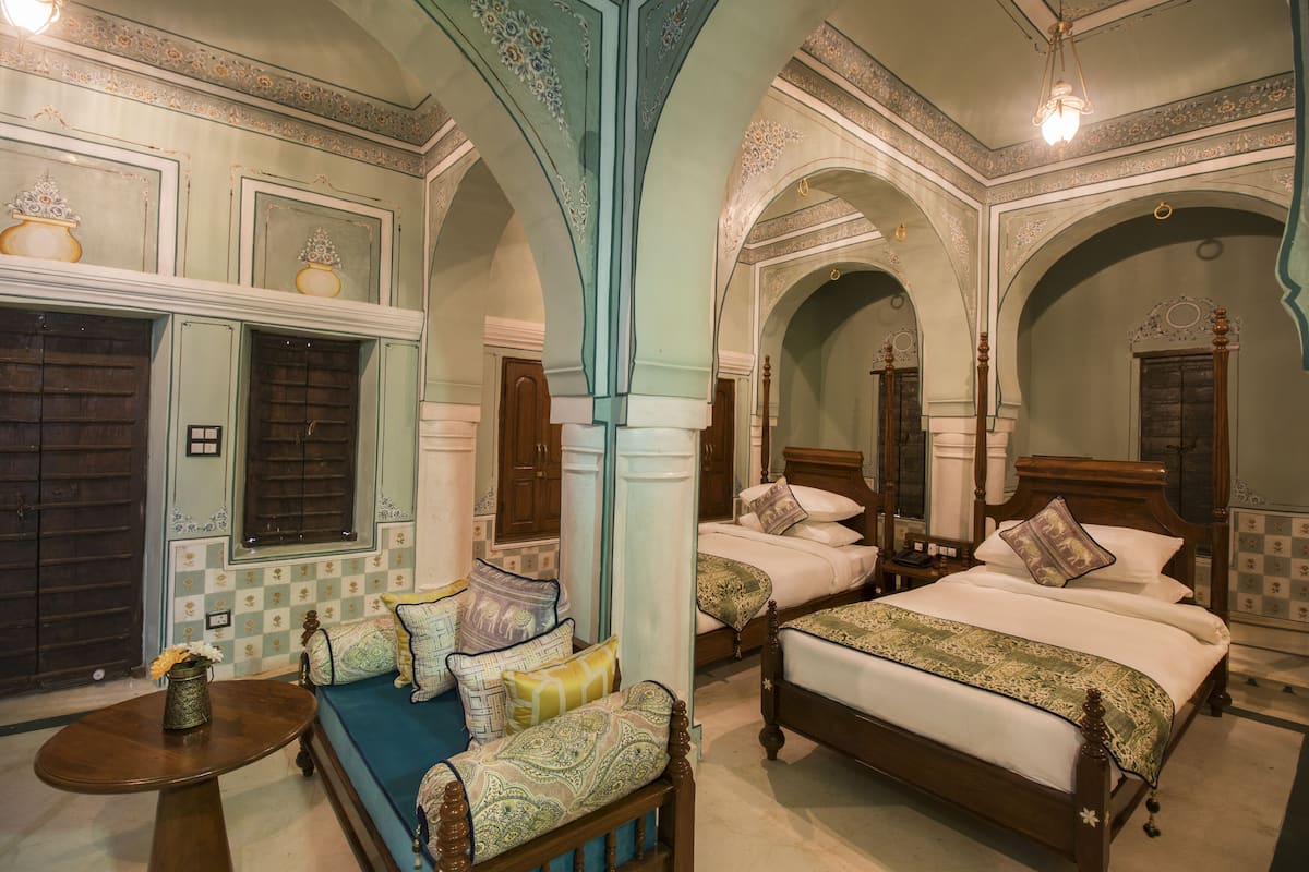 A traditional room with two beds, a sofa, and a small table.