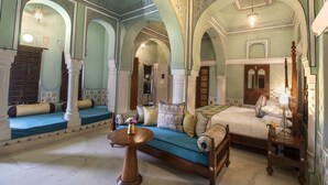A room with a bed, a sofa, and a table, featuring ornate arches and a chandelier. - The Legacy Mandawa (Jhunjhunu)