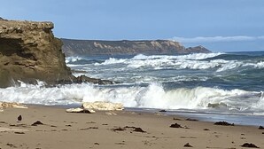 A beach with rocky cliffs and waves crashing onto the shore. - Salt Bush - Great views nestled  in the moonahs (St Andrews Beach)