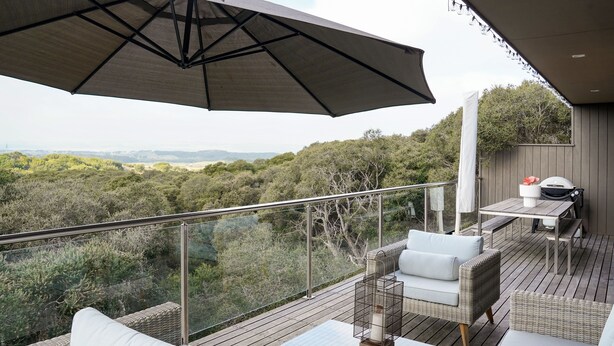A balcony with wicker furniture, a glass table, and a view of the countryside. - Salt Bush - Great views nestled  in the moonahs (St Andrews Beach)