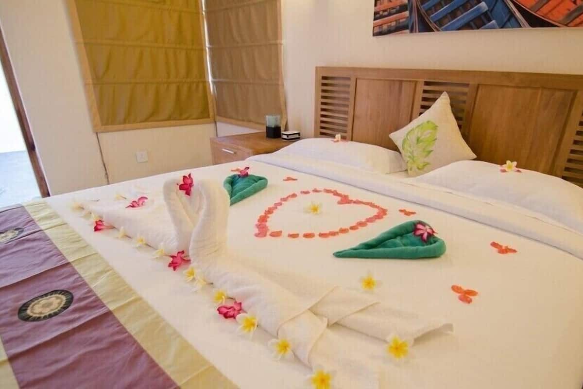 A neatly made bed with floral decorations and a heart design on the bedspread.