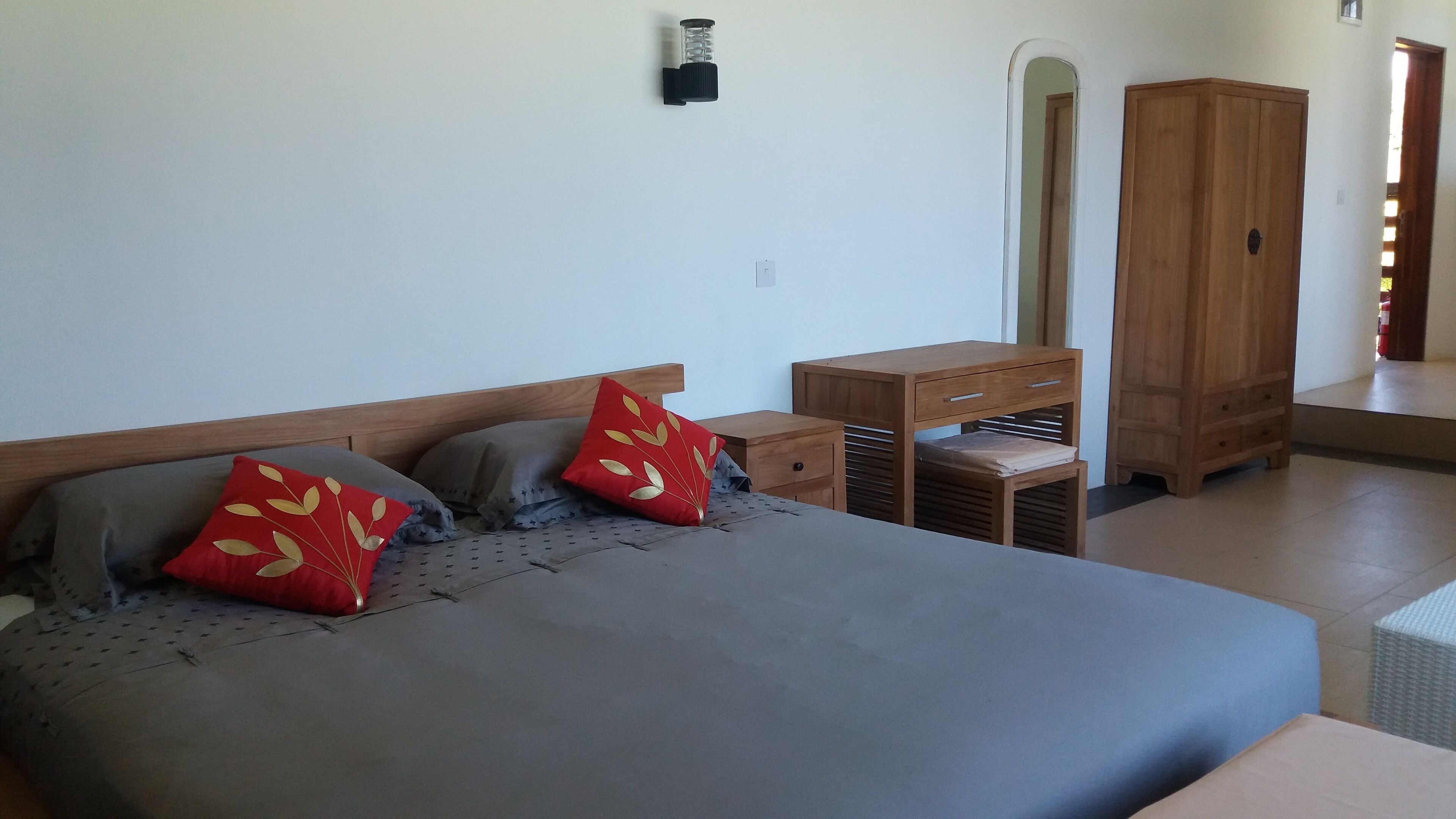 A bedroom with a bed, two nightstands, a wooden wardrobe, and a small table.