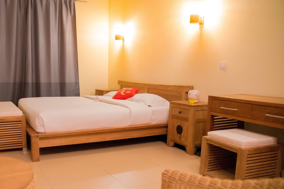 A neatly arranged bedroom with a wooden bed, bedside tables, a bench, and a desk.