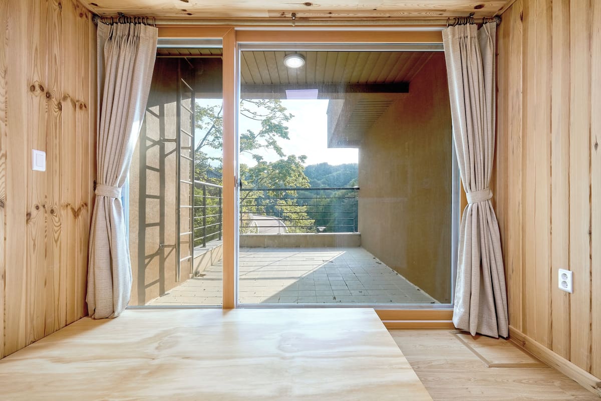 A wooden interior with a sliding glass door leading to an outdoor balcony.