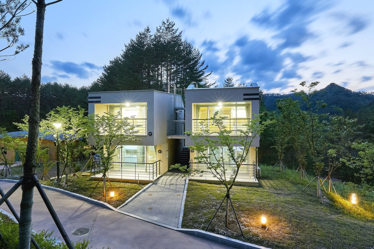 A modern two-story building with large windows and a paved entrance area.