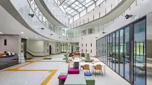 A spacious indoor area with multiple levels, glass walls, and a central seating area with tables and chairs. - Geumgangsong Ecorium (Uljin)