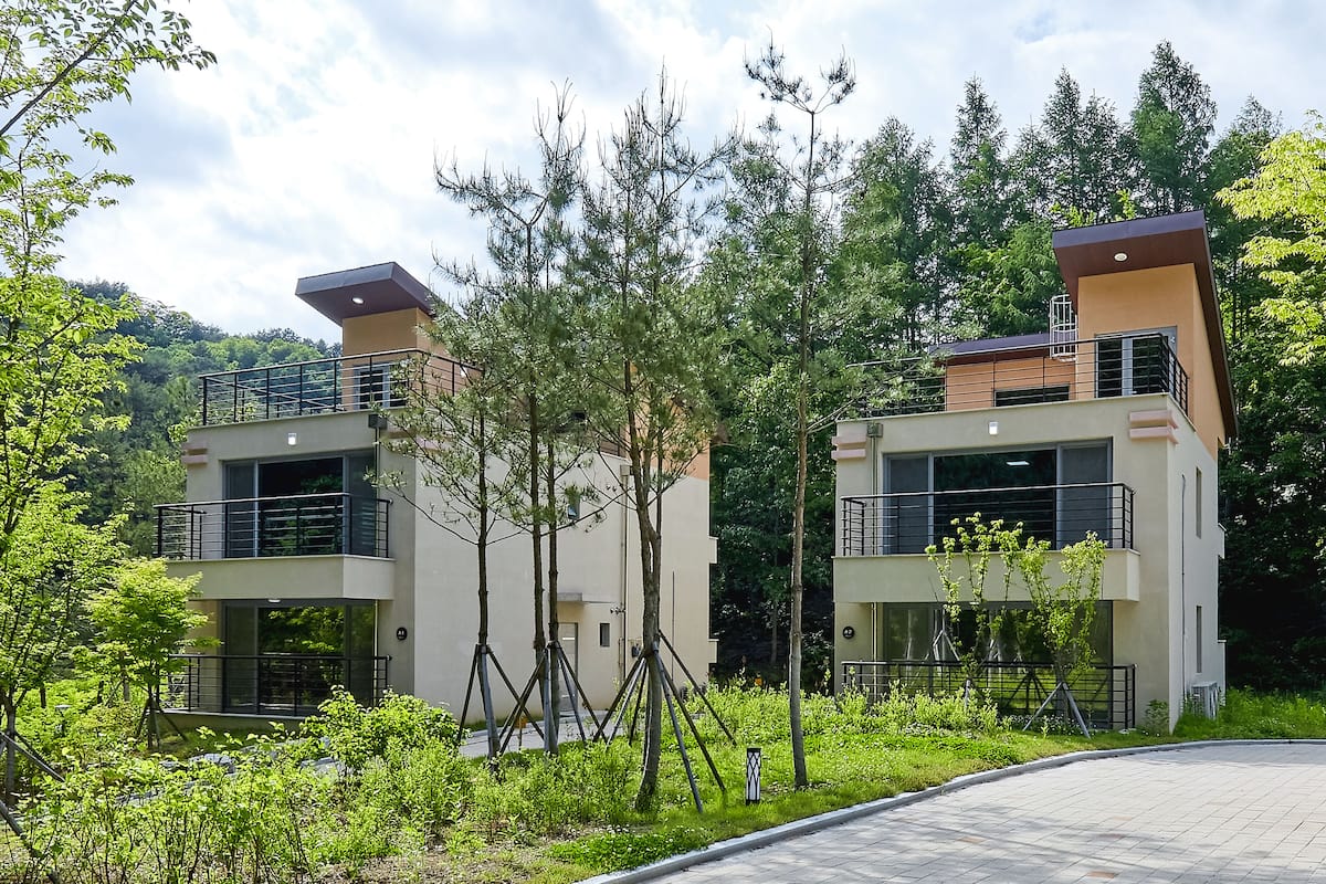 A modern two-story building with balconies and a landscaped garden.