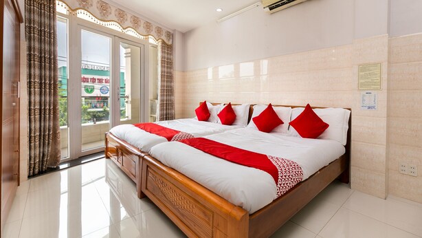 Une chambre d’hôtel avec un grand lit, un balcon avec des rideaux et un climatiseur fixé au mur.