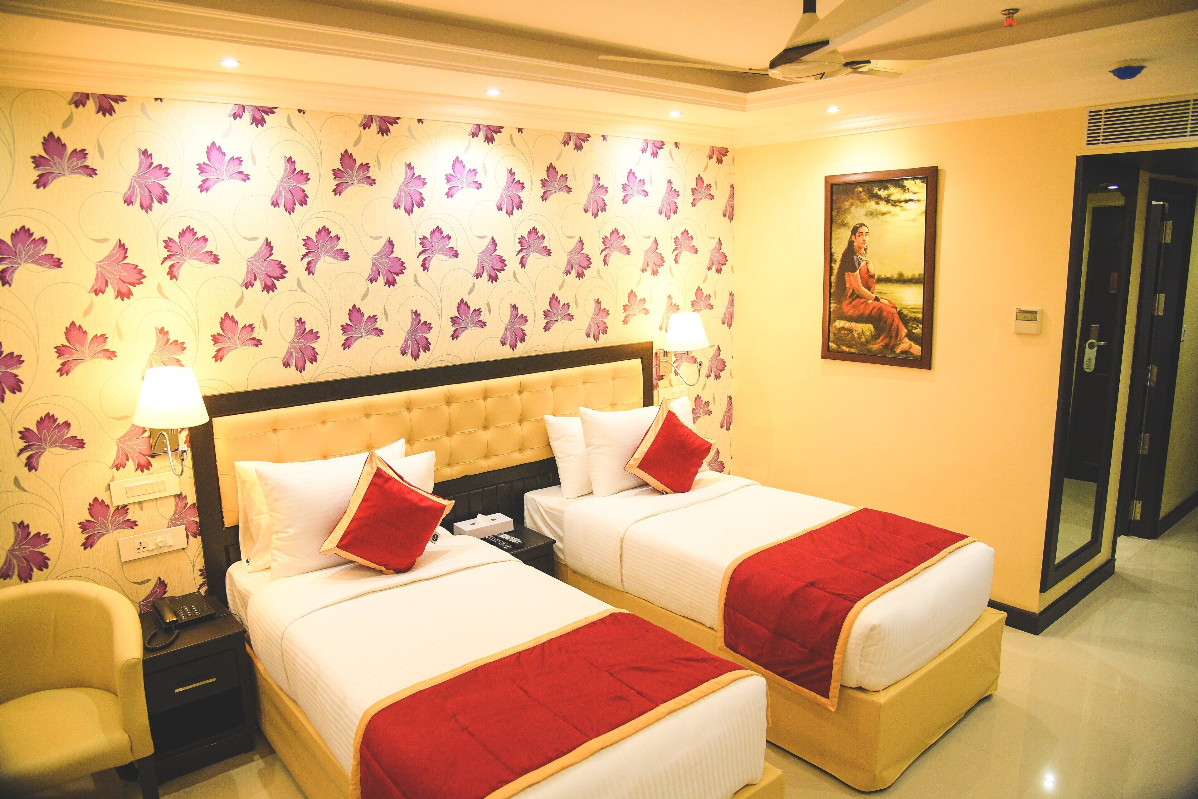 A hotel room with two beds, a large painting on the wall, and a door to the right.