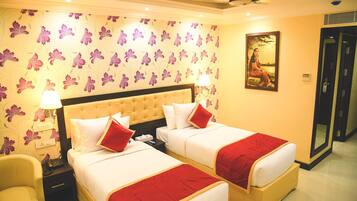 A hotel room with two beds, a large painting on the wall, and a door to the right.